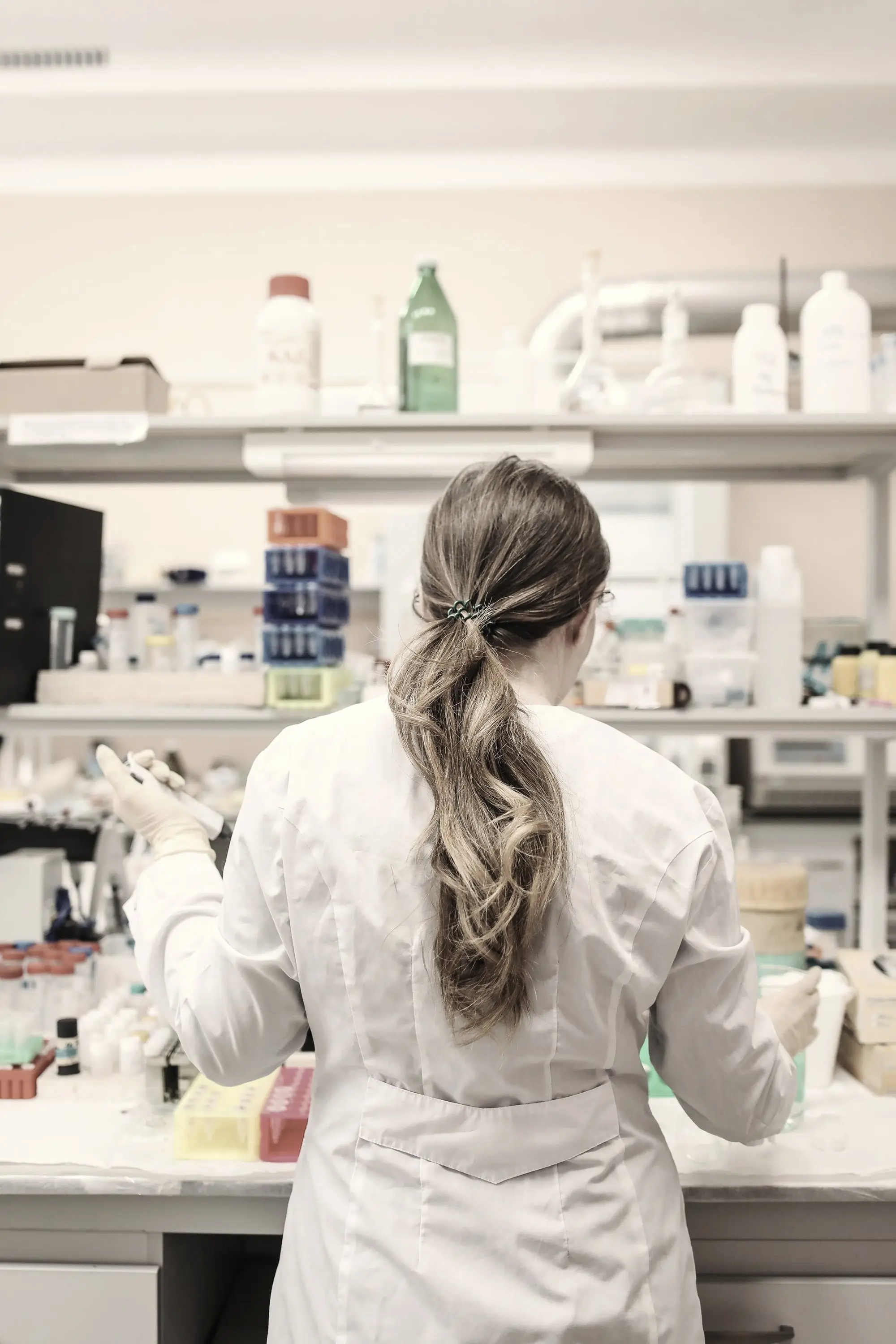 Mokslininkė laboratorijoje, nugara į žiūrovą